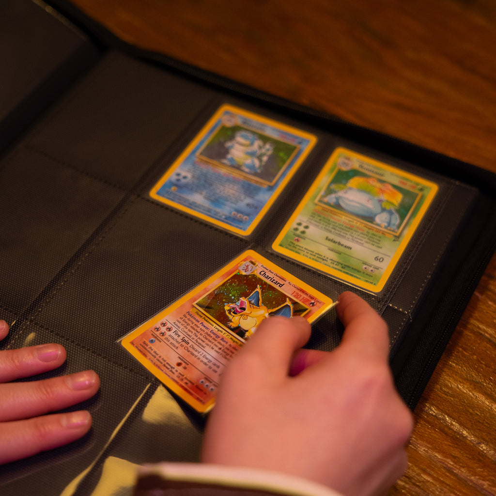 hand die een Charizard Pokémonkaart in een Luxafox binder stopt